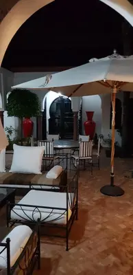 a room with tables and chairs and an umbrella at Villa avec piscine a Marrakech in Marrakech