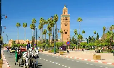 a horse drawn carriage on a city street with a clock tower at Villa avec piscine a Marrakech in Marrakech