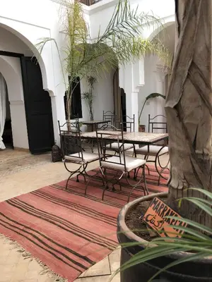 a room with a table and chairs on a rug at Riad Sin in Marrakech