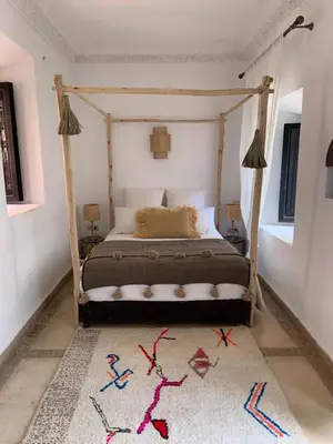 a bedroom with a canopy bed with a rug at Riad Sin in Marrakech