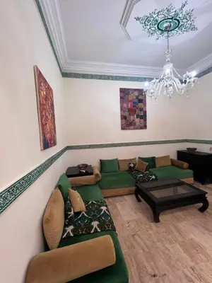 a living room with green couches and a chandelier at Dar Tariq 3 suites avec pisicine in Marrakech