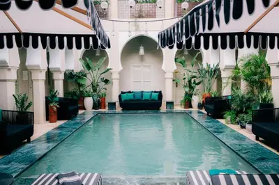 an indoor pool in a building with chairs and plants at Riad Nashira & Spa in Marrakech