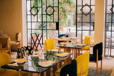 a dining room with tables and chairs and windows at Riad Nashira & Spa in Marrakech