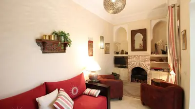 a living room with a red couch and a fireplace at Riad Kasbah Baraka in Marrakech