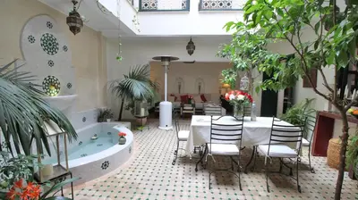 a room with a bath tub and a table and chairs at Riad Kasbah Baraka in Marrakech