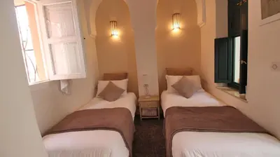 three beds in a small room with two windows at Riad Kasbah Baraka in Marrakech