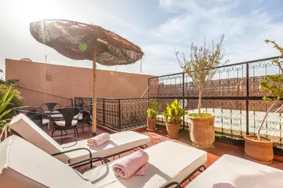 a patio with chairs and an umbrella on a balcony at Exclusive private Riad in Marrakech