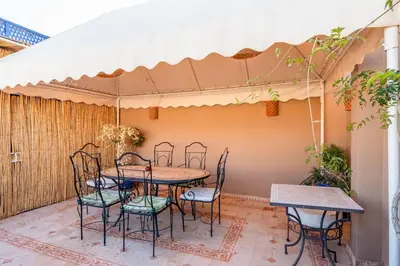 a patio with a table and chairs under awning at RIAD AWINATI Location Privatisée ,piscine chauffée , beau Rooftop in Marrakech