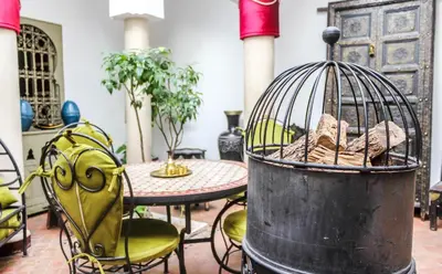 a bird cage sitting next to a table with chairs at Riad Minorisa in Marrakech