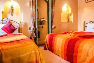 a bedroom with two beds with orange and red blankets at Riad Minorisa in Marrakech