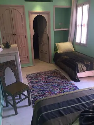 a bedroom with a bed and a chair and a rug at Riad Tahani in Marrakech