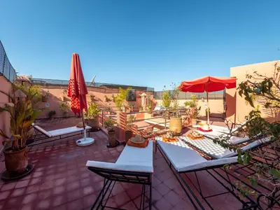 a patio with tables and chairs and an umbrella at Riad Tahani in Marrakech