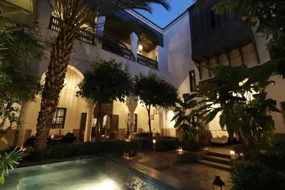 a courtyard of a building with a swimming pool and palm trees at Riad Zaouia 44 in Marrakech