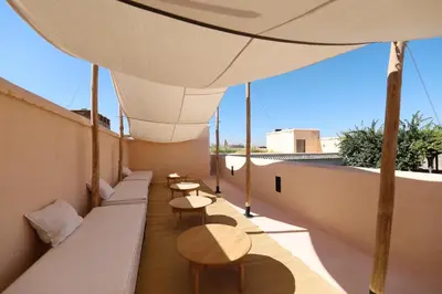a balcony with tables and benches on a roof at Riad Zaouia 44 in Marrakech