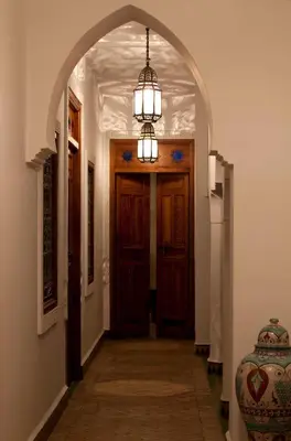 an arched hallway with a door and a chandelier at Riad Les Bougainvilliers in Marrakech