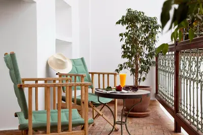 a balcony with two chairs and a table with a drink at Riad Les Bougainvilliers in Marrakech