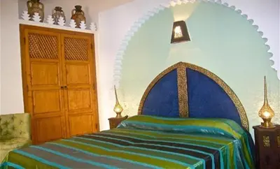 a bedroom with a bed with a blue and green blanket at Riad Rabahsadia in Marrakech