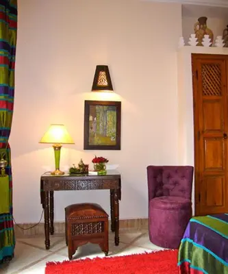 a bedroom with a table and a chair and a lamp at Riad Rabahsadia in Marrakech