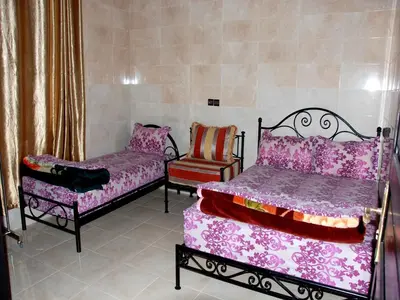 a bedroom with two beds and a chair at Appartements Ziad Guéliz in Marrakech