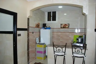 a kitchen with two chairs and a counter with a refrigerator at Appartements Ziad Guéliz in Marrakech