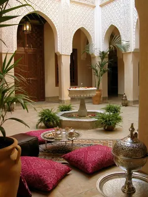 a courtyard with a fountain in a building with red pillows at Riad Kniza in Marrakech