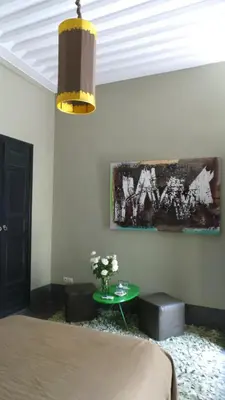 a bedroom with a bed and a table and a painting at Riad First in Marrakech
