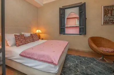 a bedroom with a bed and a window and a chair at Riad D'ari in Marrakech