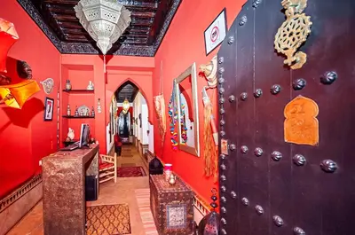 a room with a red wall with a wooden door at Riad Dar Nadwa in Marrakech