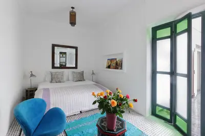 a bedroom with a bed and two blue chairs at Riad Albatoul in Marrakech