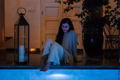 a woman sitting on the edge of a swimming pool at Riad Albatoul in Marrakech