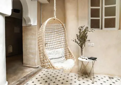 a wicker swing chair in a room with a table at Riad SHIRAZ in Marrakech