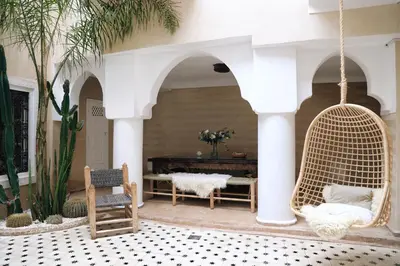 a porch with a swinging chair and a table at Riad SHIRAZ in Marrakech