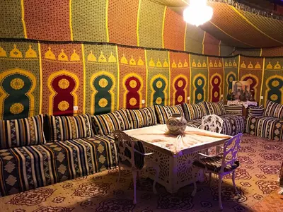 a room with a table and chairs and a wall at Hostel Dream belko in Marrakech