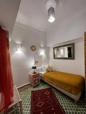 a bedroom with a bed and a table and a mirror at Riad Andalla in Marrakech