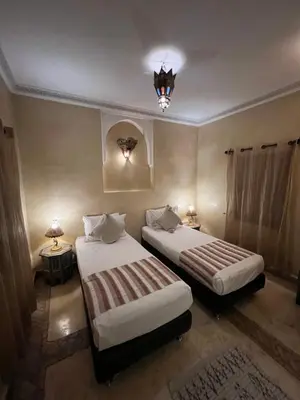 a bedroom with two beds and a chandelier at Riad Andalla in Marrakech