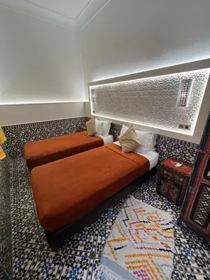 two brown beds in a room with a rug at Riad Andalla in Marrakech