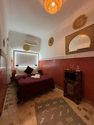 a bedroom with a bed and a table and a mirror at Riad Andalla in Marrakech