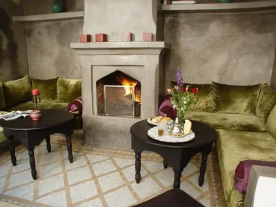 a living room with a fireplace and a couch and tables at Dar Rocmarra in Marrakech
