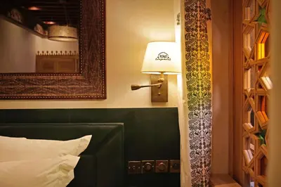 a bedroom with a bed with a green headboard and a lamp at Elegancia Riad Boutique & SPA in Marrakech
