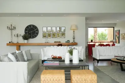 a living room with white furniture and a clock on the wall at Villa BELYA in Marrakech