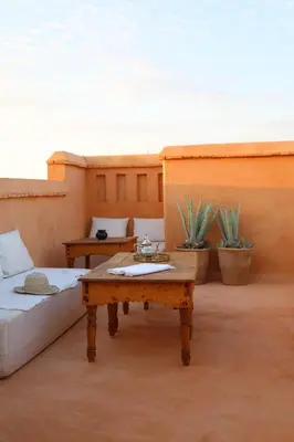 a room with a table and a bed and some plants at Riad Azzouna 13 in Marrakech