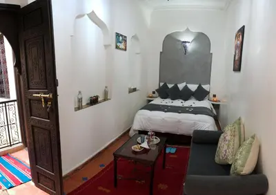 a bedroom with a bed and a couch and a table at Dar Asdika in Marrakech