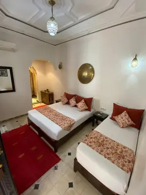 a bedroom with two beds and a red rug at Dar Asdika in Marrakech