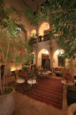 a living room with tables and chairs and trees at Riad Mur Akush in Marrakech