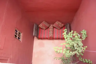 a red wall with a window and a potted plant at Riad El Youssoufi in Marrakech