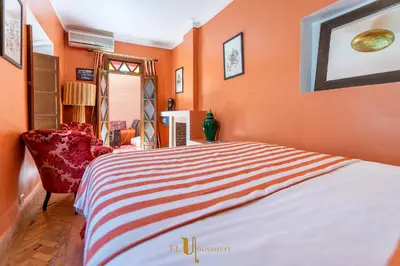 a orange bedroom with a bed and a chair at Riad El Youssoufi in Marrakech