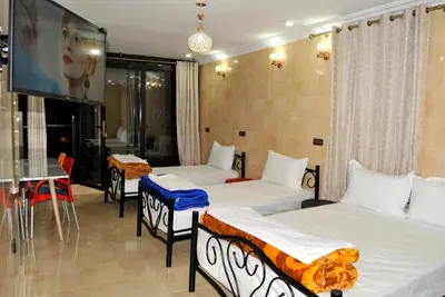 two beds in a room with a tv and a table at Silia in Marrakech
