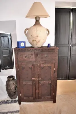 a vase on top of a wooden cabinet with a lamp on top at Riad Essaada in Marrakech
