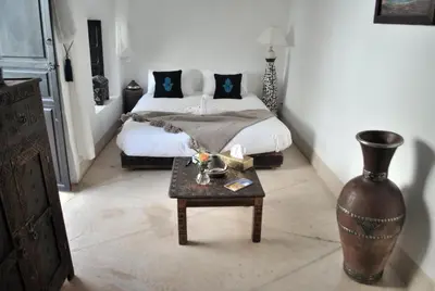 a bedroom with a bed and a table with a vase at Riad Essaada in Marrakech