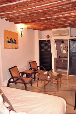 a room with a bed and chairs and a table at Riad Essaada in Marrakech